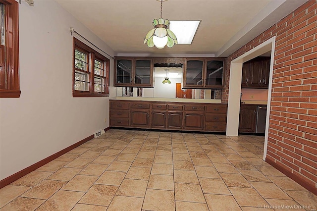 820 Sharon Dr, Cape Girardeau, MO 63701 - kitchen featuring glass insert cabinets, light countertops, pendant lighting, dark brown cabinets, and brick wall