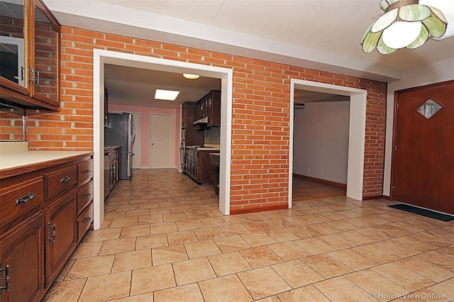 820 Sharon Dr, Cape Girardeau, MO 63701 - kitchen featuring light countertops, freestanding refrigerator, built in microwave, brick wall, and under cabinet range hood
