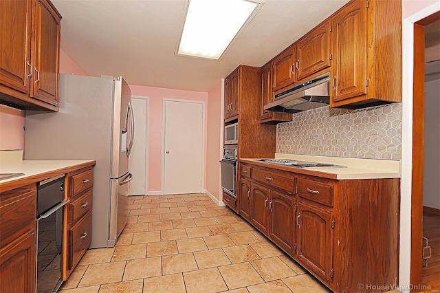 820 Sharon Dr, Cape Girardeau, MO 63701 - kitchen with black oven, tasteful backsplash, light countertops, under cabinet range hood, and stainless steel fridge