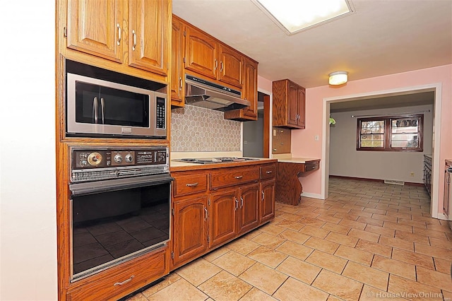 820 Sharon Dr, Cape Girardeau, MO 63701 - kitchen with black oven, stainless steel microwave, under cabinet range hood, decorative backsplash, and light countertops