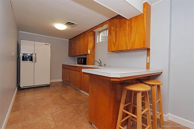 820 Sharon Dr, Cape Girardeau, MO 63701 - kitchen featuring white fridge with ice dispenser, brown cabinetry, a sink, light countertops, and baseboards