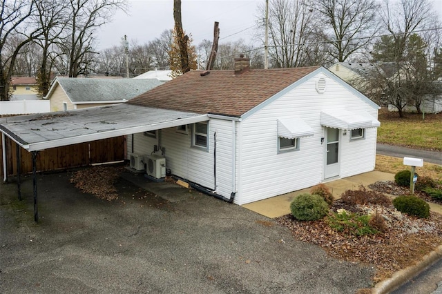 601 E Jefferson St, Ofallon, IL 62269 - back of house featuring roof with shingles, a chimney, a cooling unit, a carport, and asphalt driveway