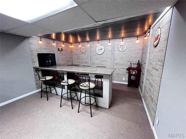 1034 Port Perry Dr, Perryville, MO 63775 - indoor dry bar with baseboards, rail lighting, brick wall, speckle patterned floor, and a drop ceiling