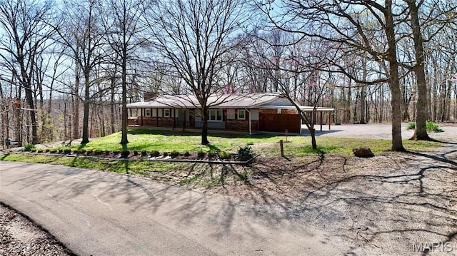 1034 Port Perry Dr, Perryville, MO 63775 - ranch-style home featuring a front lawn, a forest view, and covered porch