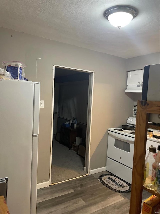 10272 Imperial Dr, Saint Louis, MO 63136 - kitchen with white appliances, under cabinet range hood, wood finished floors, white cabinetry, and baseboards