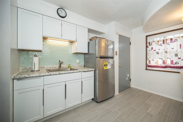 10144 Dellridge Ln, Saint Louis, MO 63136 - kitchen with a sink, freestanding refrigerator, decorative backsplash, baseboards, and white cabinets