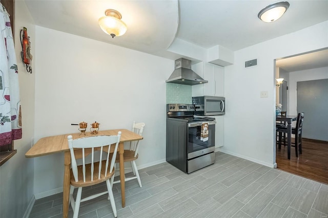 10144 Dellridge Ln, Saint Louis, MO 63136 - kitchen featuring wall chimney range hood, stainless steel appliances, white cabinetry, and baseboards