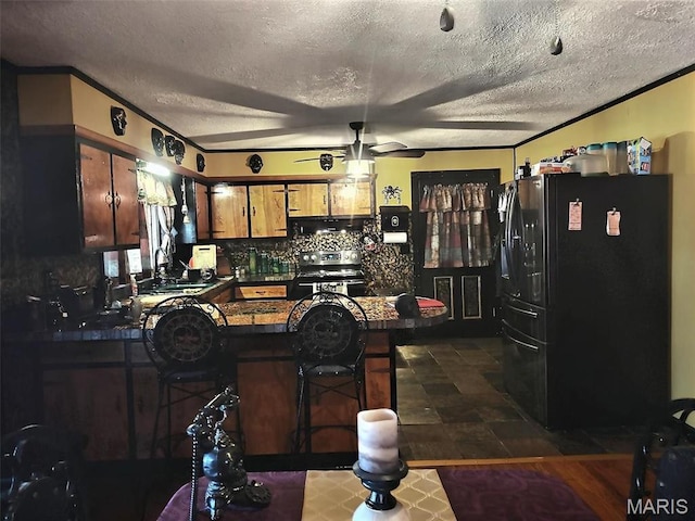 813 Kendall Dr, Poplar Bluff, MO 63901 - kitchen with freestanding refrigerator, dark countertops, a peninsula, stainless steel electric range, and a ceiling fan