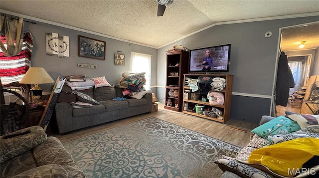 living area with ornamental molding, wood finished floors, a ceiling fan, lofted ceiling, and a textured ceiling