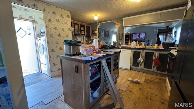 kitchen featuring white dishwasher, light wood finished floors, wallpapered walls, a textured ceiling, and white cabinets