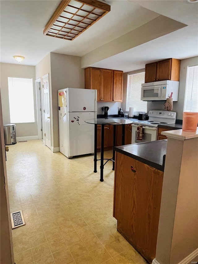 4934 W Florissant Ave, Saint Louis, MO 63115 - kitchen featuring white appliances, dark countertops, brown cabinets, light floors, and baseboards