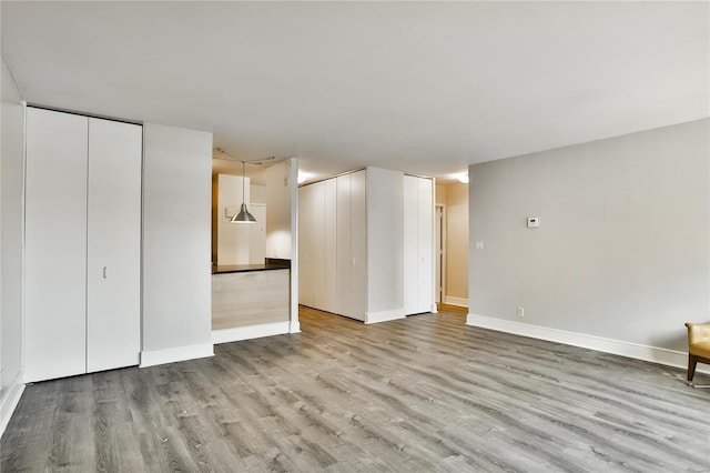 unfurnished living room with wood finished floors and baseboards