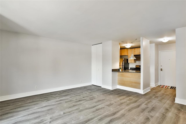 unfurnished living room with wood finished floors and baseboards