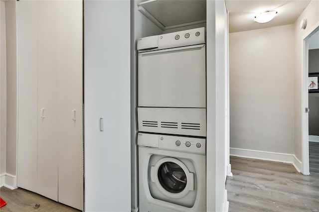 laundry area featuring estacked washer and dryer, wood finished floors, and baseboards