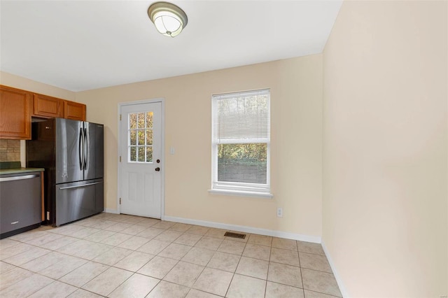 1443 Alberta Dr, Saint Charles, MO 63303 - kitchen with dishwasher, freestanding refrigerator, baseboards, light tile patterned flooring, and brown cabinetry