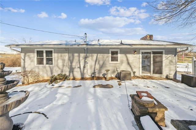 snow covered property featuring a chimney and central AC unit
