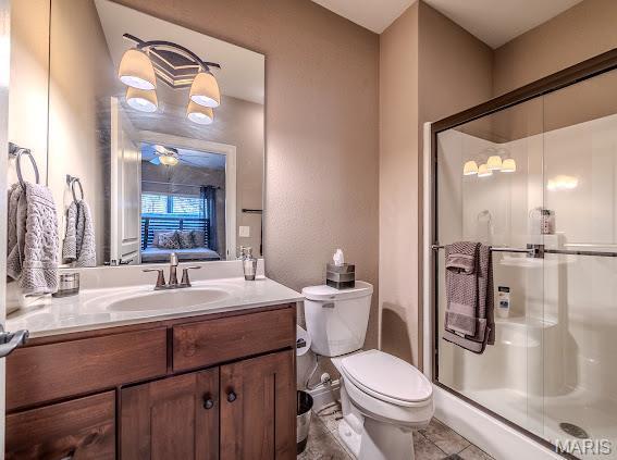 3168 Twin Rivers Pt, Camdenton, MO 65420 - bathroom featuring a shower stall, vanity, toilet, a ceiling fan, and tile patterned floors
