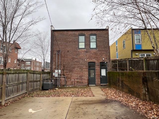 back of property featuring brick siding, a fenced backyard, cooling unit, and a patio area