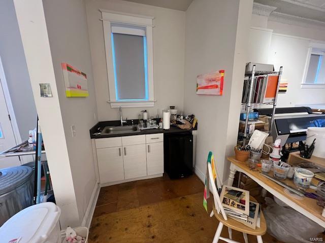kitchen with a sink, dark countertops, white cabinets, and baseboards