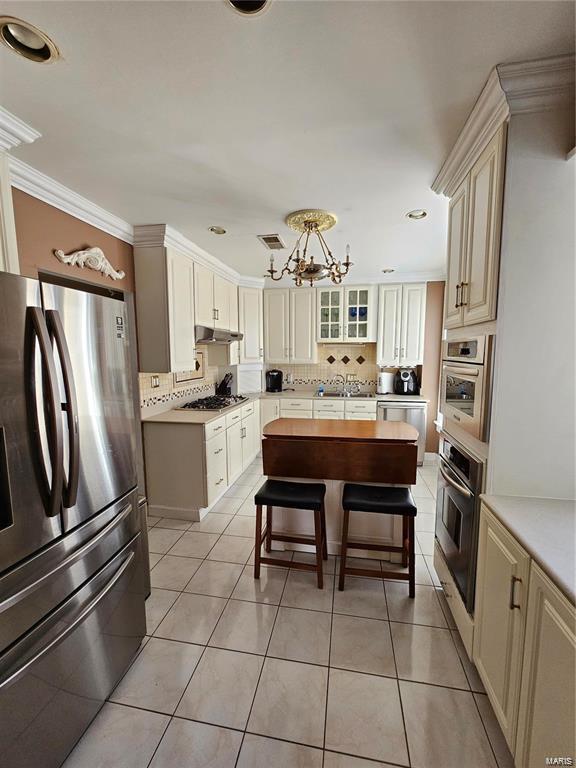 14 N Kingshighway Blvd Unit 6Bs, Saint Louis, MO 63108 - kitchen featuring stainless steel appliances, under cabinet range hood, a chandelier, decorative backsplash, and recessed lighting