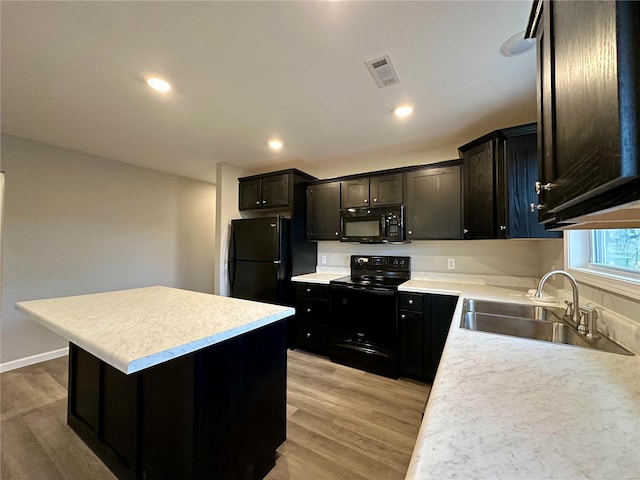 16 N Herren Ave, Ellsinore, MO 63937 - kitchen featuring black appliances, a sink, a kitchen island, light countertops, and light wood-style floors