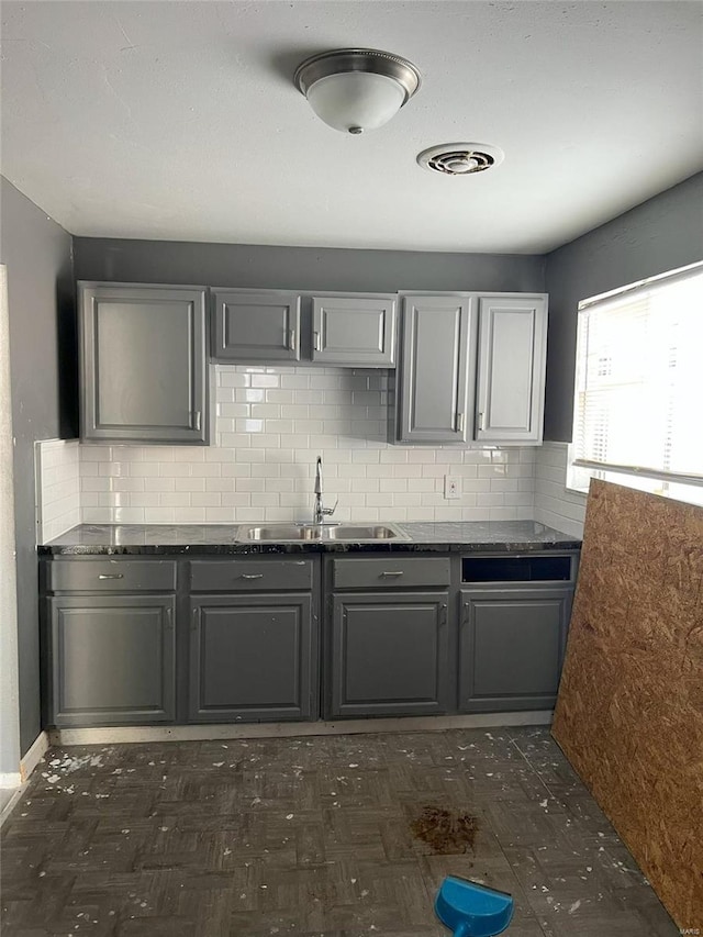 4610 Lexington Ave, Saint Louis, MO 63115 - kitchen featuring a sink, gray cabinetry, dark countertops, and backsplash