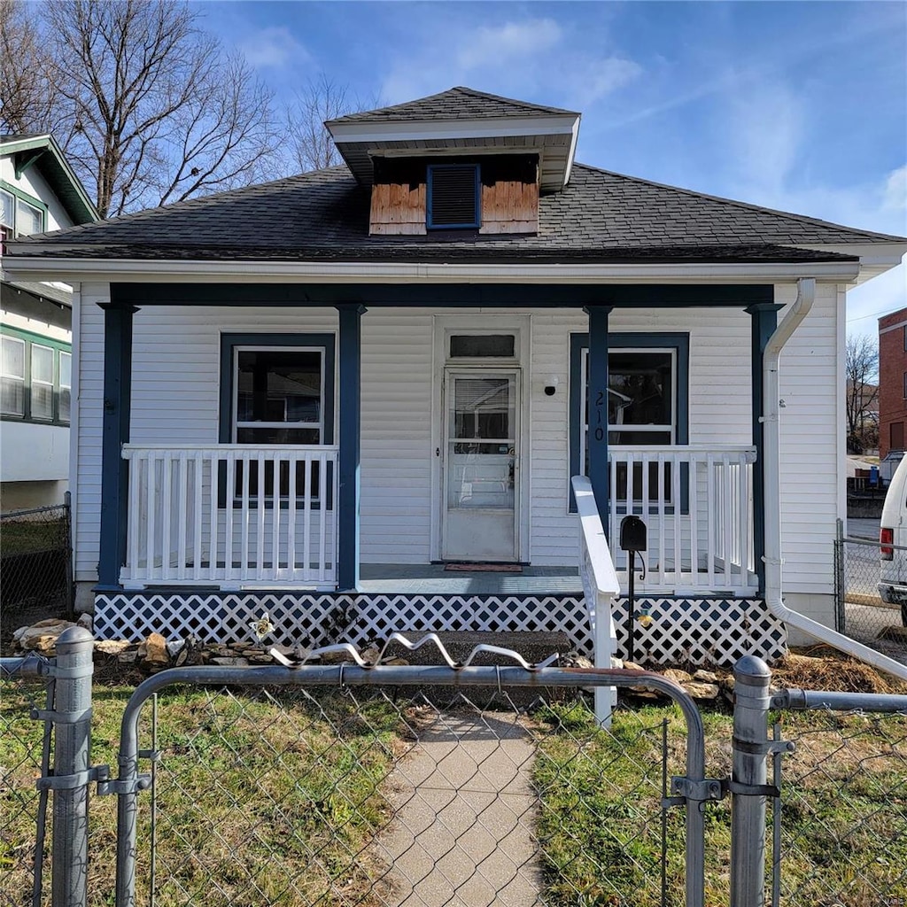 shotgun-style home with a porch, a gate, and a shingled roof