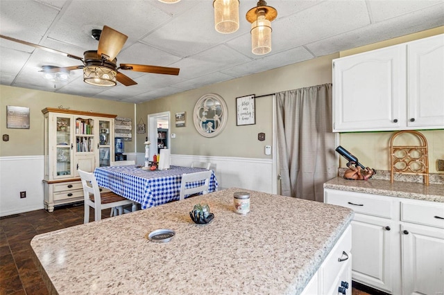 10751 State Route F, Farmington, MO 63640 - kitchen with white cabinets, ceiling fan, a wainscoted wall, a center island, and a paneled ceiling