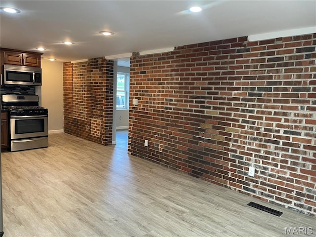 3305 Fee Fee Rd, Bridgeton, MO 63044 - kitchen featuring appliances with stainless steel finishes, brick wall, light wood-style floors, and baseboards