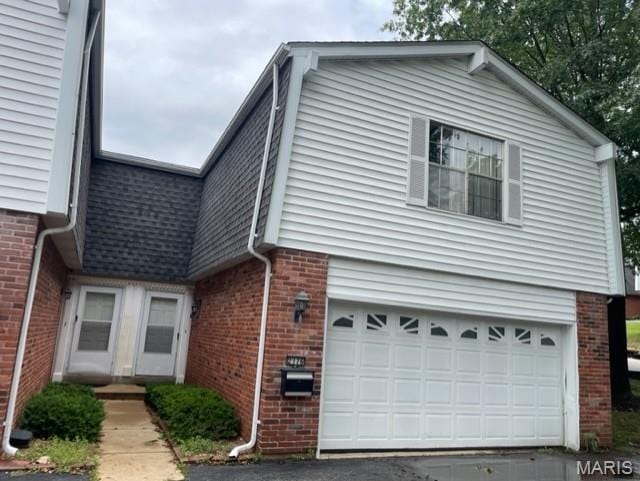 view of front facade with brick siding, an attached garage, and asphalt driveway