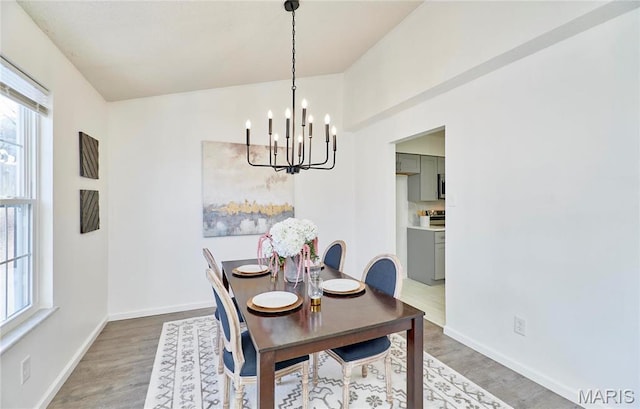 dining area featuring a chandelier, light wood-type flooring, and baseboards