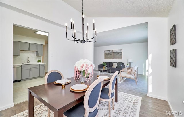 dining room with vaulted ceiling, a chandelier, light wood-type flooring, and baseboards