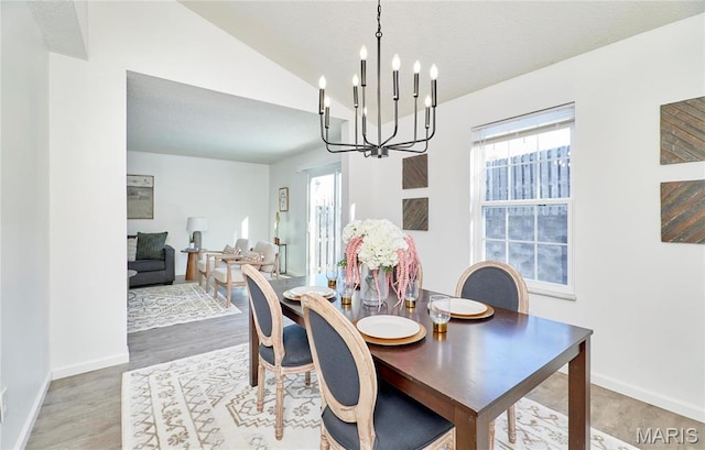 dining area with a chandelier, lofted ceiling, baseboards, and wood finished floors