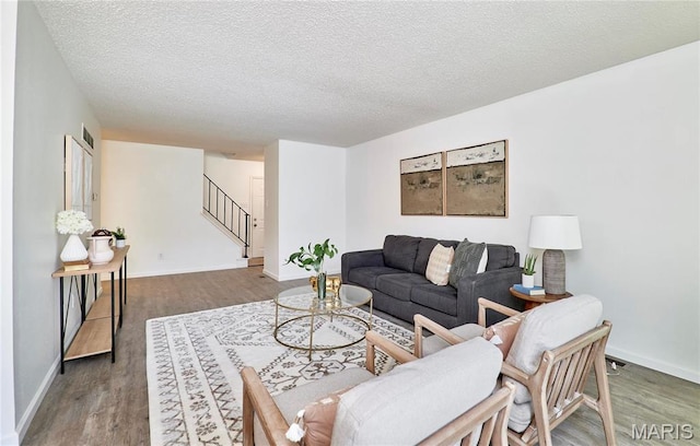 living area with stairway, wood finished floors, a textured ceiling, and baseboards