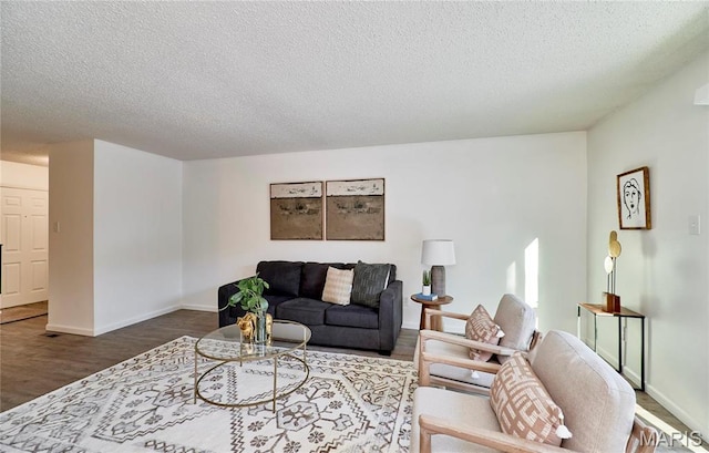 living area featuring a textured ceiling, wood finished floors, and baseboards