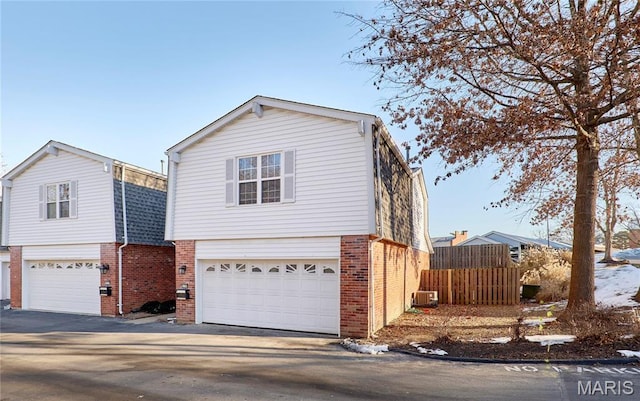 view of front facade featuring brick siding, an attached garage, fence, and driveway