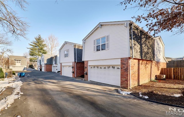 view of front of house with brick siding, a garage, driveway, and a residential view
