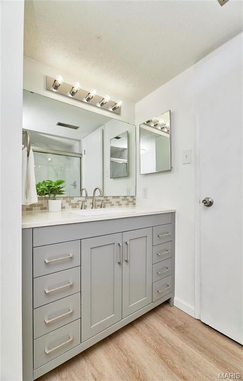 full bath featuring wood finished floors, vanity, and decorative backsplash