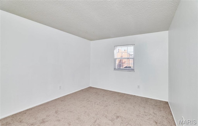 carpeted spare room featuring a textured ceiling and baseboards
