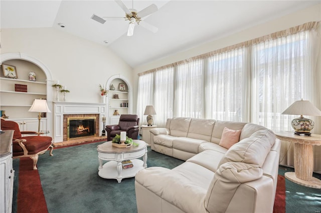 living room featuring built in shelves, a ceiling fan, lofted ceiling, a fireplace, and carpet flooring
