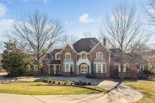 colonial home with french doors, a front yard, and a chimney