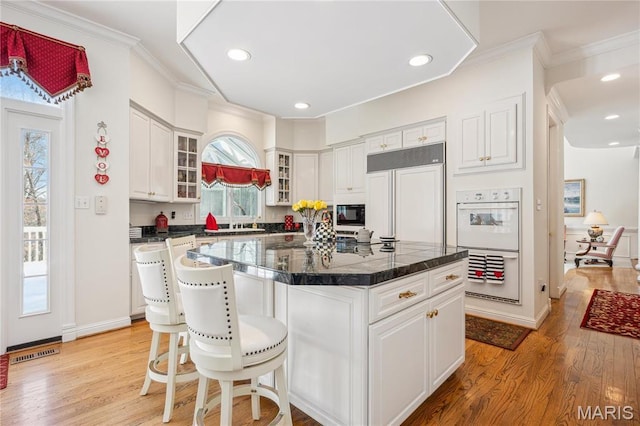 19385 Deer Pointe Estates Dr, Wildwood, MO 63038 - kitchen featuring built in appliances, light wood-style flooring, glass insert cabinets, white cabinetry, and crown molding