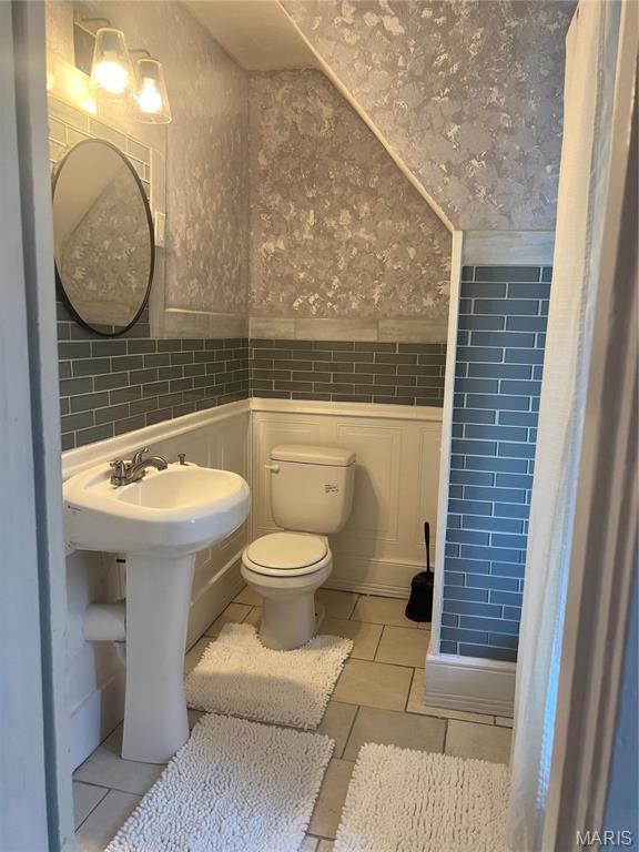 3511 Oakdale Ave, Saint Louis, MO 63121 - bathroom featuring wallpapered walls, tile walls, tile patterned flooring, wainscoting, and toilet