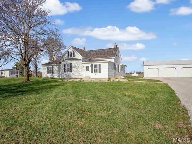 view of front of home with a chimney, a garage, an outbuilding, and a front yard