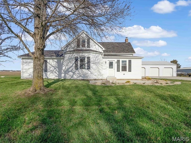 view of front of house featuring a chimney, a front lawn, entry steps, and a detached garage