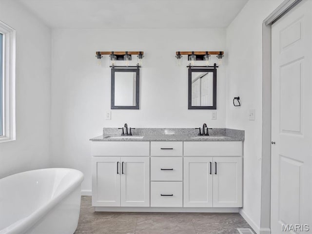 bathroom with a soaking tub, double vanity, baseboards, and healthy amount of natural light