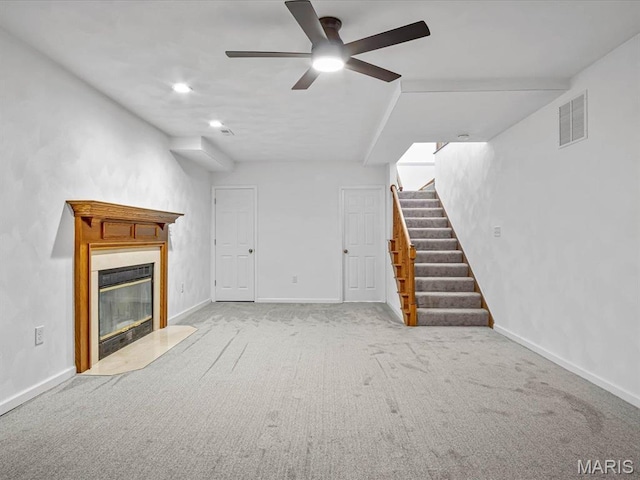 unfurnished living room featuring stairs, a glass covered fireplace, ceiling fan, carpet, and baseboards
