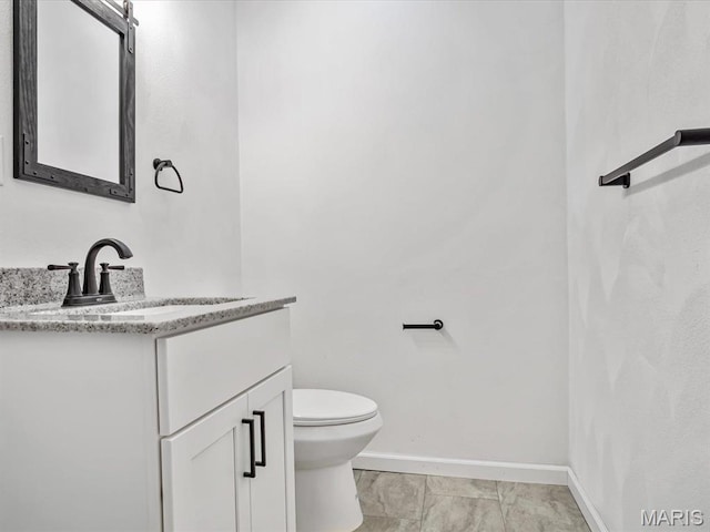 half bathroom featuring baseboards, vanity, and toilet