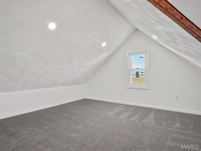 additional living space with baseboards, dark carpet, vaulted ceiling, and recessed lighting