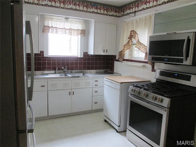 7939 Delmar Blvd Unit 1W, Saint Louis, MO 63130 - kitchen with stainless steel appliances, a sink, stainless steel counters, white cabinets, and tasteful backsplash